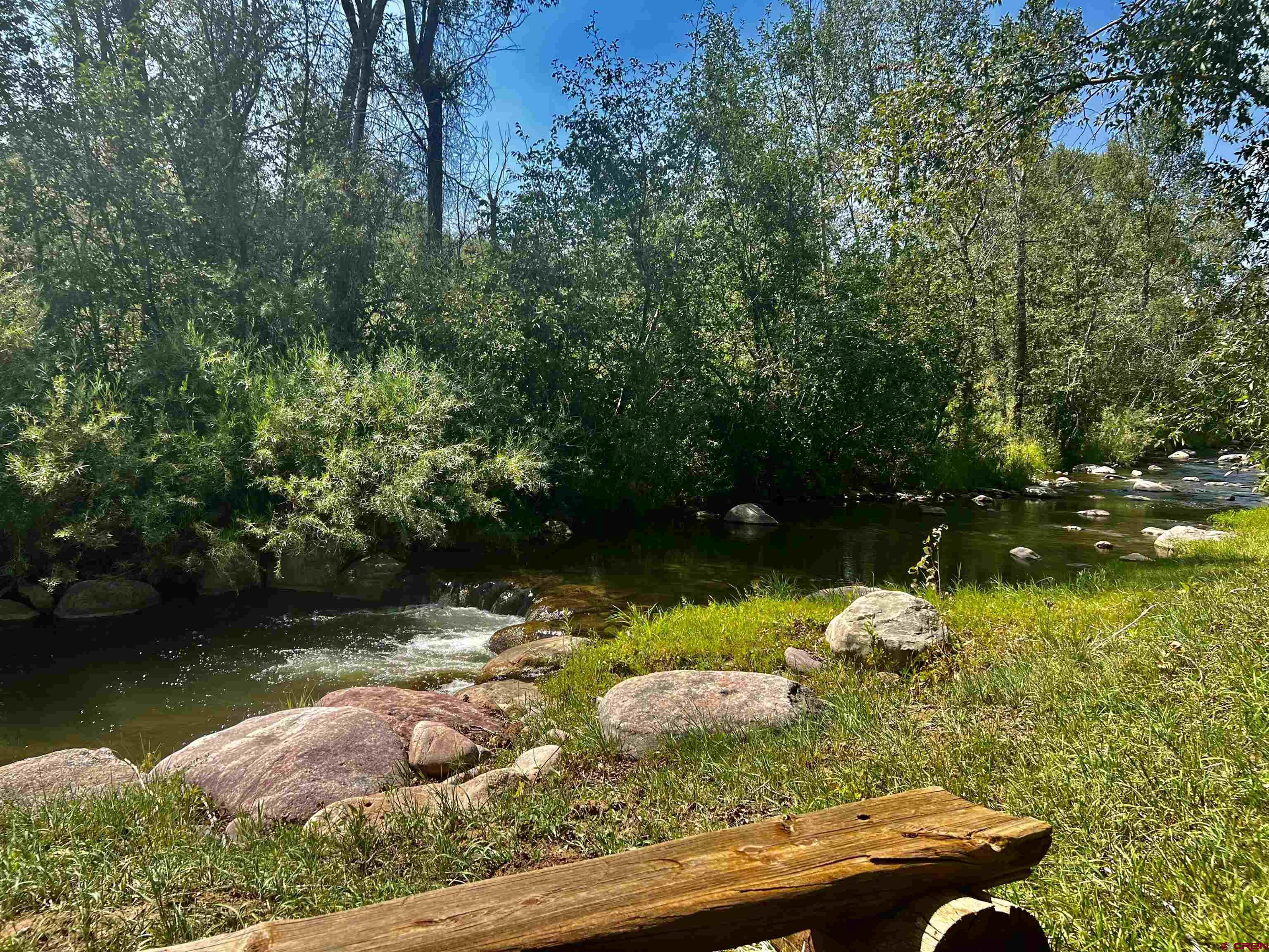 2777 County Road 225 Durango, CO 81301 - Photo 10 of 35 a view of a lake with lawn chairs and large trees