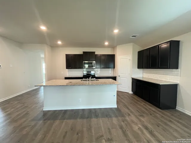 a living room with stainless steel appliances a flat screen tv and kitchen view