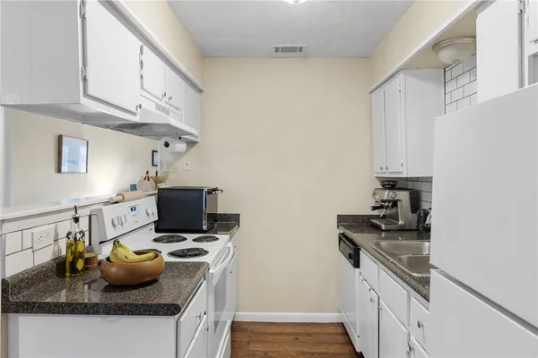 a kitchen with granite countertop a sink stove and cabinets