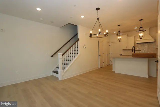 a view of a room with wooden floor staircase and kitchen appliances