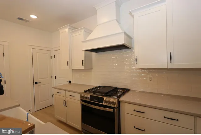 a kitchen with stainless steel appliances a stove and white cabinets