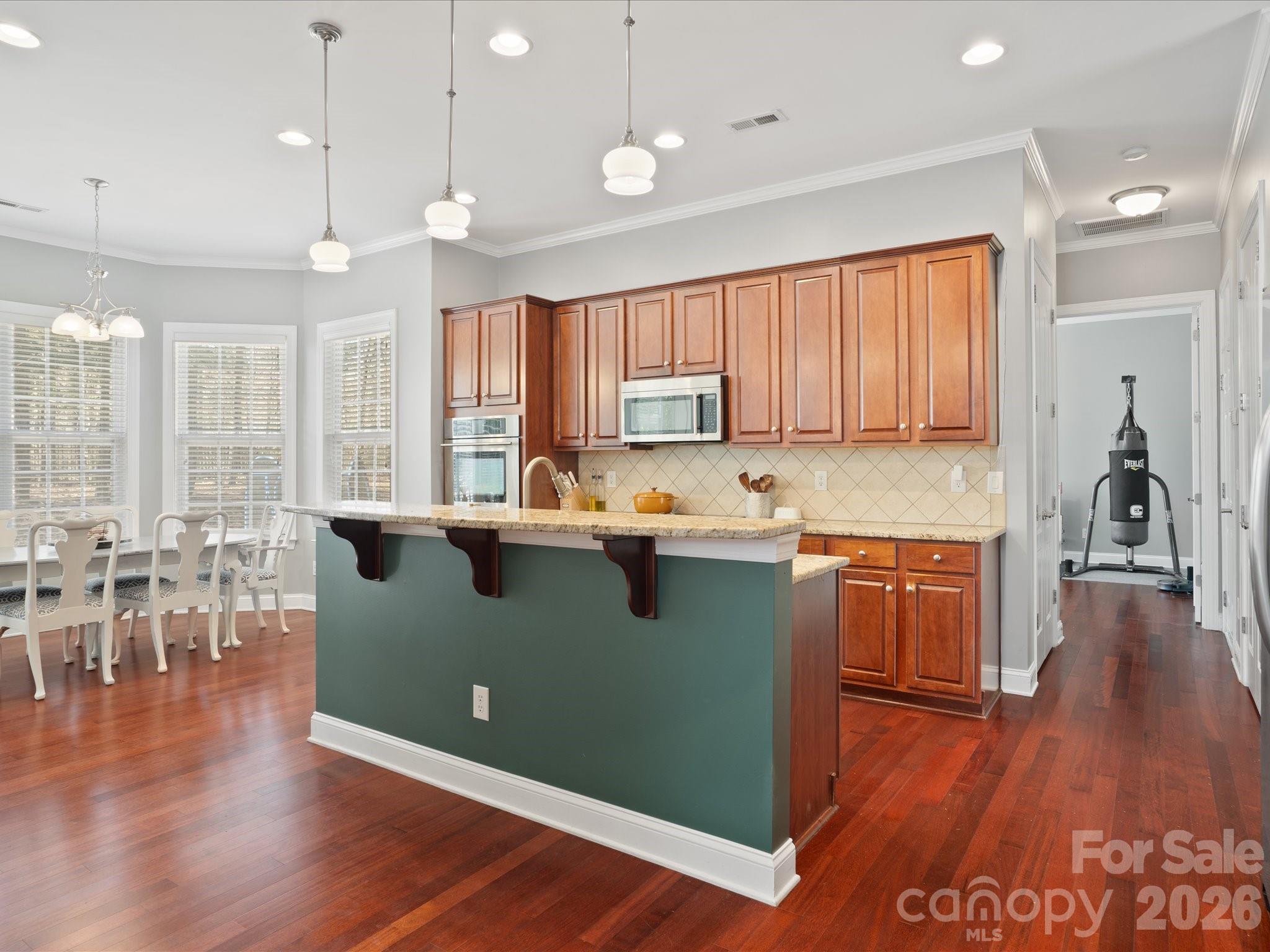 567 Quicksilver Trail Fort Mill, SC 29708 - Photo 13 of 37 a kitchen with granite countertop a stove top oven a sink a dining table and chairs with wooden floor