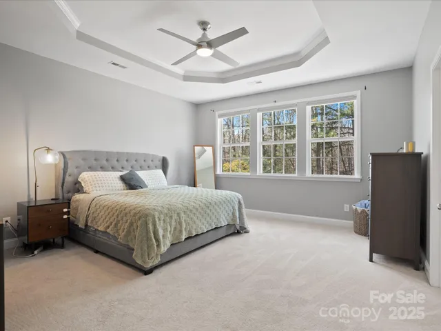 a spacious bedroom with a bed painting and a large window