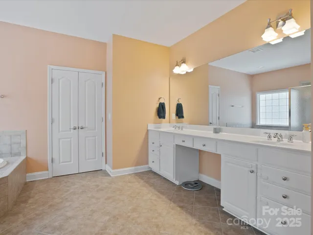 a bathroom with a double vanity sink a mirror and a bathtub