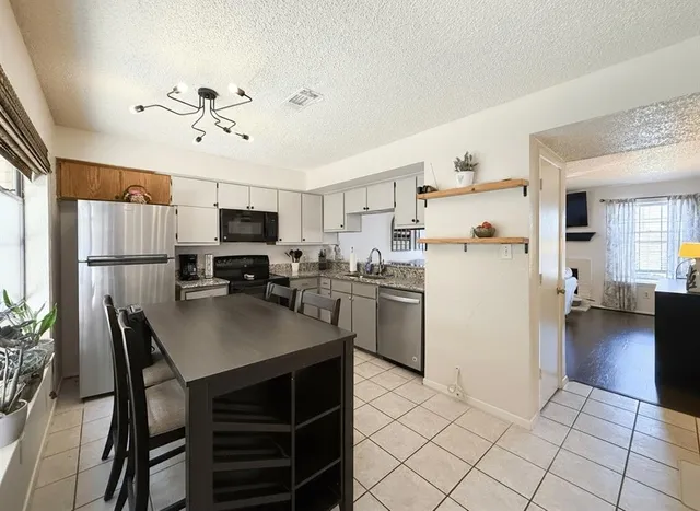 a kitchen with a refrigerator a stove sink cabinets and furniture