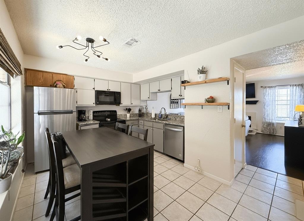1237 Dallas Drive Denton, TX 76205 - Photo 3 of 18 a kitchen with a refrigerator a stove sink cabinets and furniture