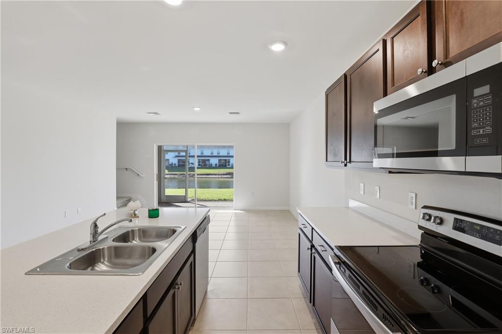 15368 Wildflower Circle Naples, FL 34119 - Photo 12 of 35 a kitchen with a sink and a stove top oven with wooden floor