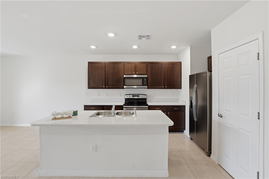 15368 Wildflower Circle Naples, FL 34119 - Photo 13 of 35 a kitchen with kitchen island stainless steel appliances a refrigerator stove a sink and a oven