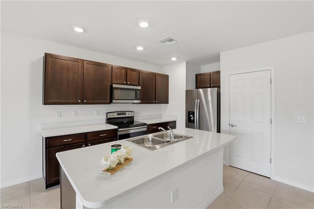 15368 Wildflower Circle Naples, FL 34119 - Photo 14 of 35 a kitchen with stainless steel appliances a microwave a sink and a refrigerator