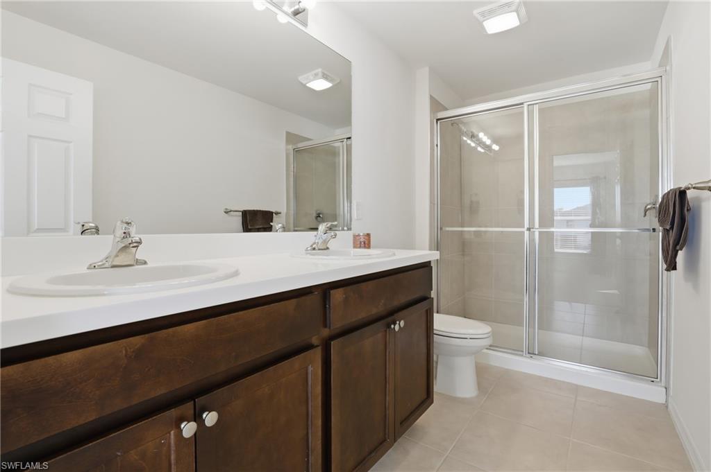 15368 Wildflower Circle Naples, FL 34119 - Photo 18 of 35 a bathroom with a double vanity sink toilet and shower