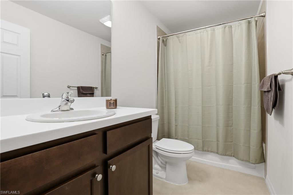15368 Wildflower Circle Naples, FL 34119 - Photo 20 of 35 a bathroom with a sink a toilet a mirror and shower curtain