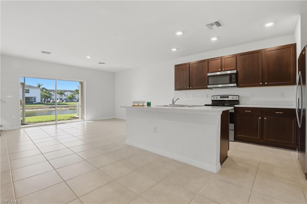 15368 Wildflower Circle Naples, FL 34119 - Photo 4 of 35 a kitchen with stainless steel appliances a stove a sink a microwave a counter top and cabinets