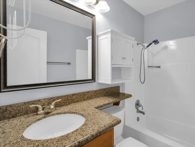 a bathroom with a granite countertop sink and a mirror