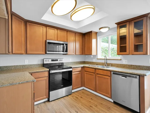 a kitchen with stainless steel appliances granite countertop a stove a sink dishwasher and a microwave oven with wooden floor