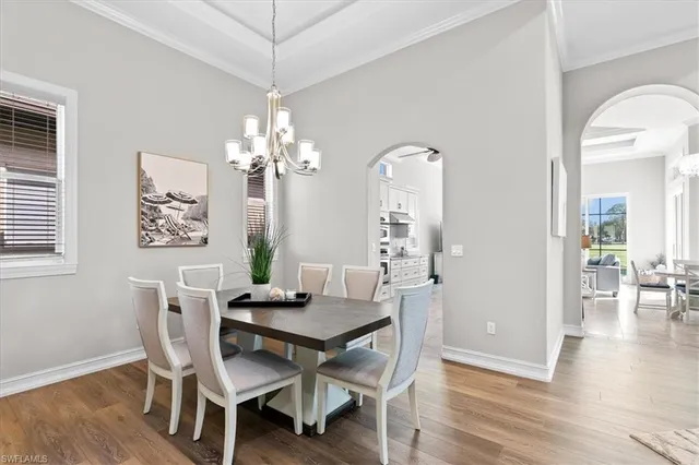 a dining room with wooden floor a chandelier a wooden table and chairs