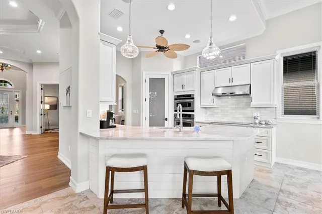 a kitchen with kitchen island a dining table chairs sink and wooden floor