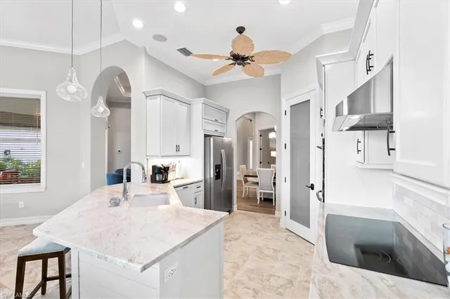 a large kitchen with stainless steel appliances a stove a refrigerator a sink a dining table and chairs with wooden floor