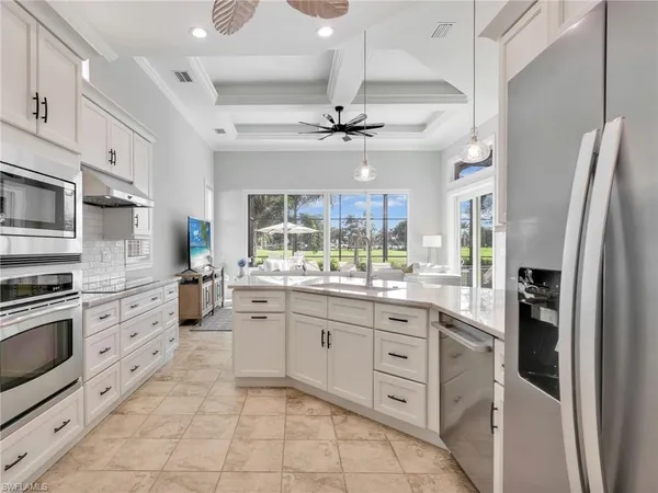 a large white kitchen with a refrigerator a stove a sink a dining table and chairs