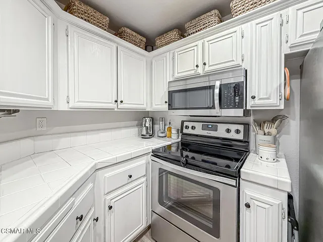 a kitchen with white cabinets and appliances