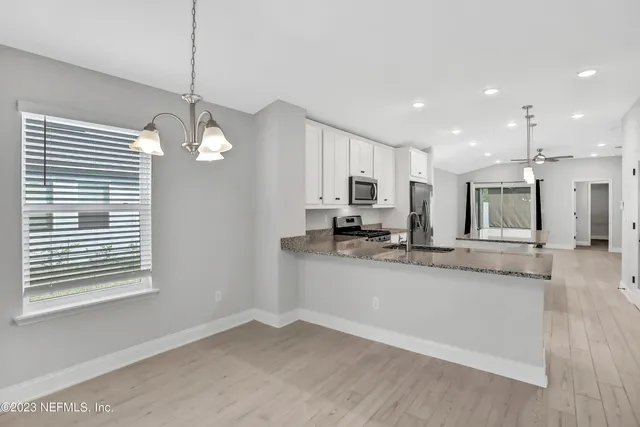 a large kitchen with granite countertop a large counter top a sink stainless steel appliances and cabinets