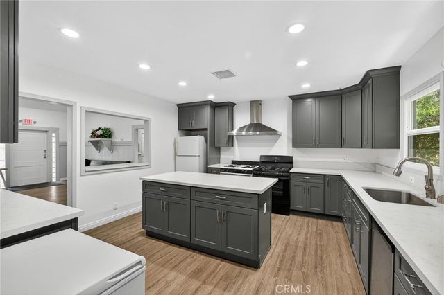 a kitchen with stainless steel appliances a sink a stove a refrigerator cabinets and wooden floor