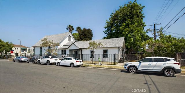 a view of road with card parked on side and retail shops