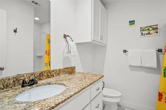 a bathroom with a granite countertop sink a toilet and a mirror