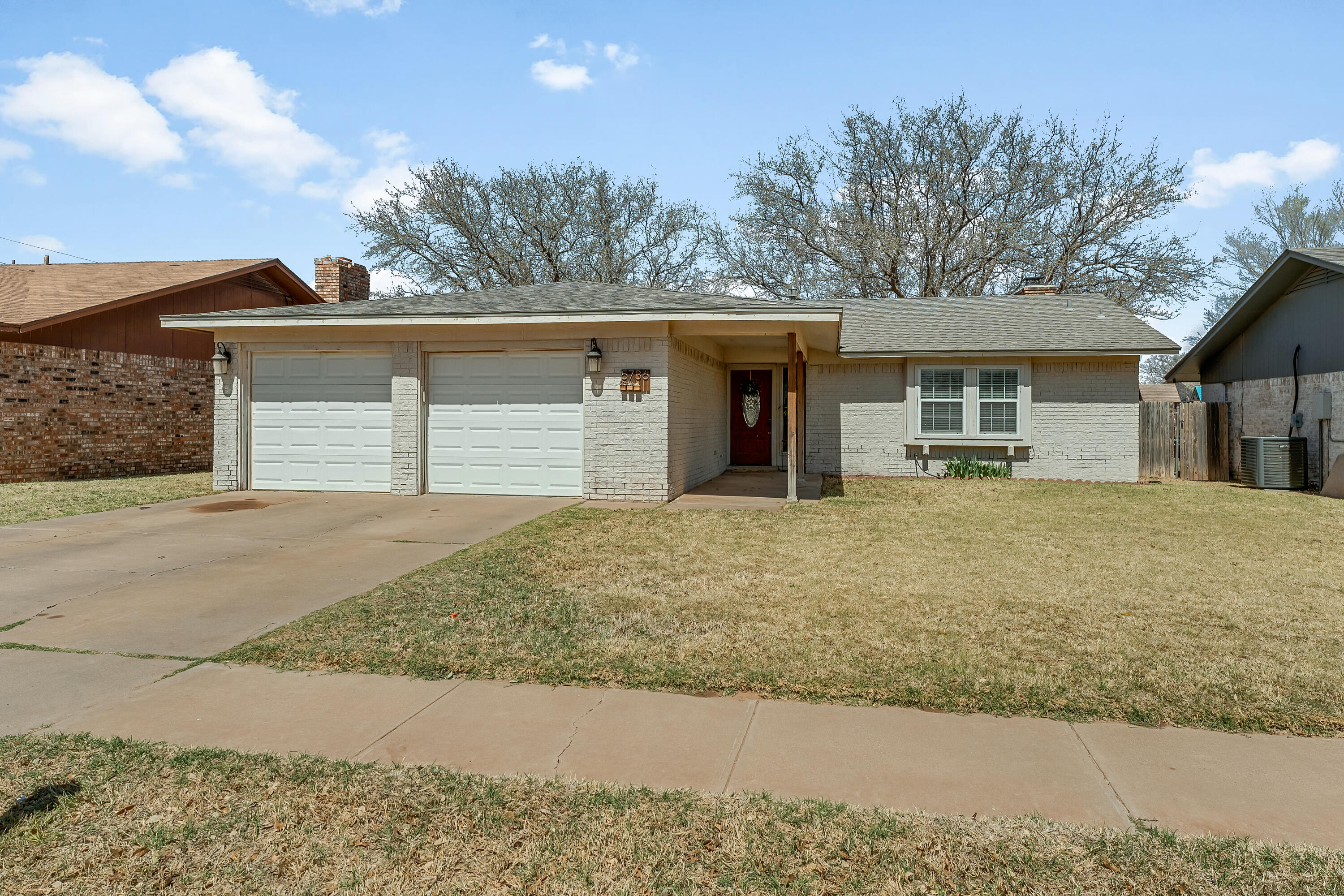 a front view of house with yard and trees in the background
