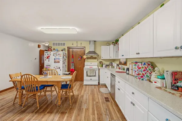 a kitchen with stainless steel appliances granite countertop a refrigerator a sink dishwasher and white cabinets with wooden floor