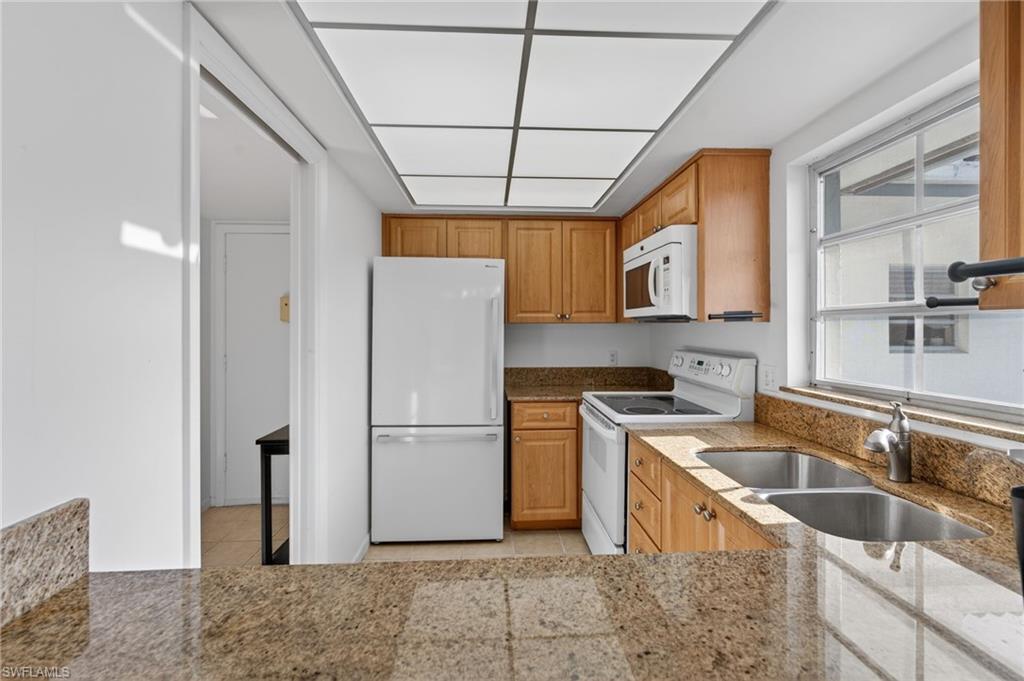 5 High Point Circle West, Unit 303 Naples, FL 34103 - Photo 10 of 36 a kitchen with stainless steel appliances granite countertop a refrigerator a sink a stove a washer and dryer