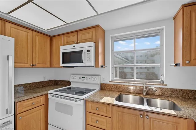 a kitchen with stainless steel appliances granite countertop a refrigerator a sink a stove a washer and dryer