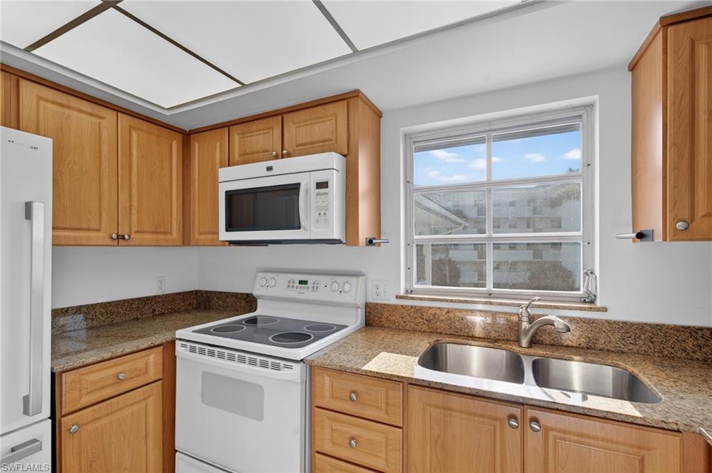 5 High Point Circle West, Unit 303 Naples, FL 34103 - Photo 11 of 36 a kitchen with a sink and a microwave oven