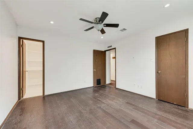 a view of empty room with wooden floor and ceiling fan