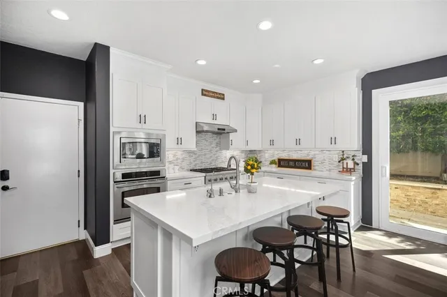 a large kitchen with granite countertop lots of counter space and stainless steel appliances