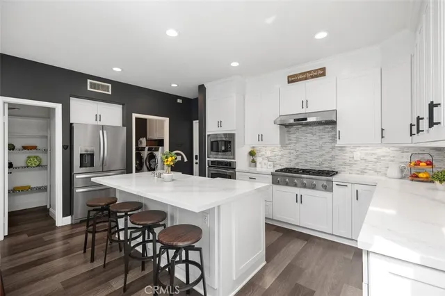 a kitchen with stainless steel appliances a stove a white cabinets and a fireplace