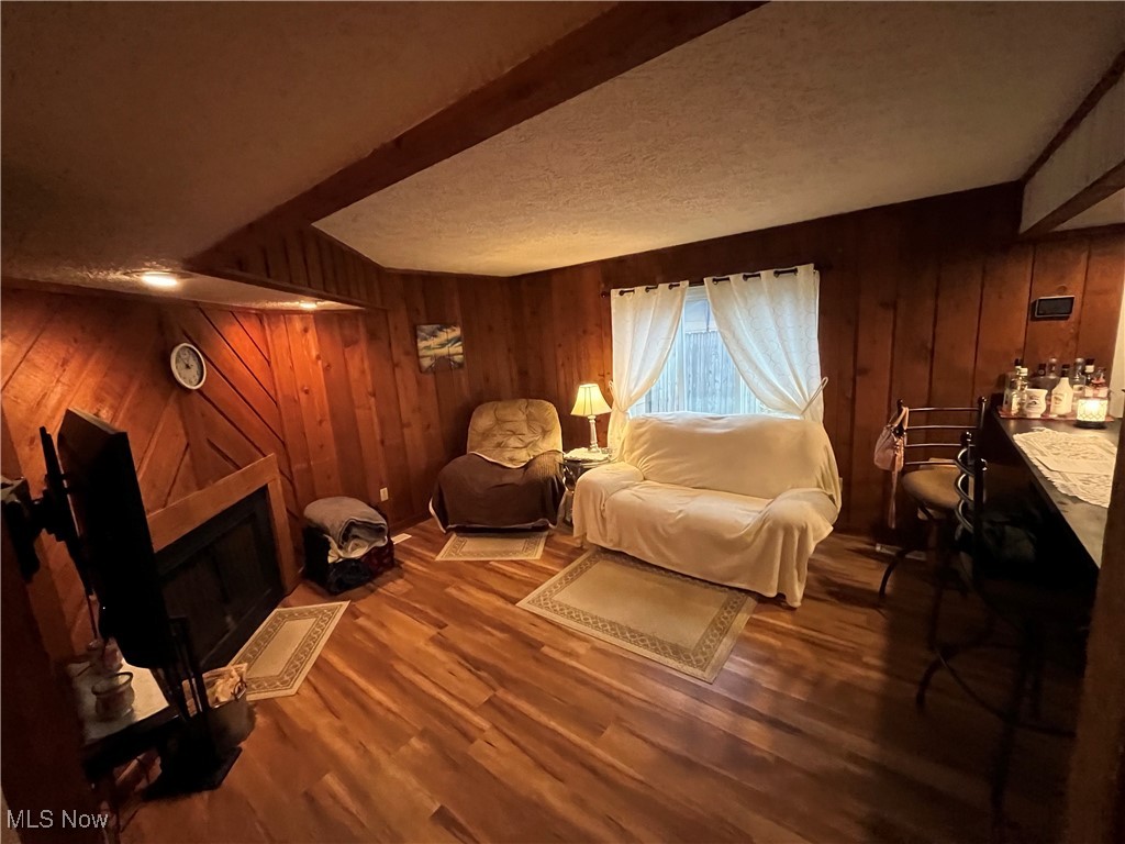 1455 Welch Road Painesville, OH 44077 - Photo 5 of 42 Living area featuring wood walls, a textured ceiling, a fireplace, and dark wood-style floors