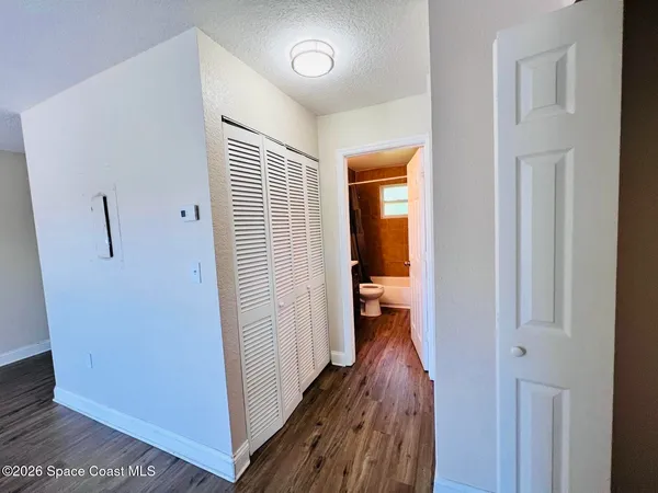 a view of a hallway with wooden floor and a bathroom
