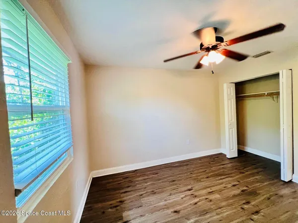 a view of a livingroom with wooden floor a ceiling fan and window