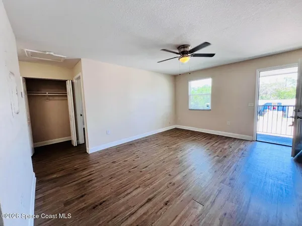 an empty room with wooden floor chandelier fan and windows