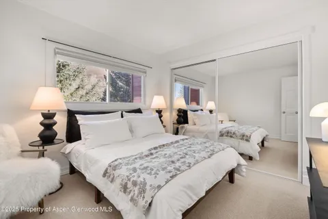 a bedroom with bed window and lamp on table