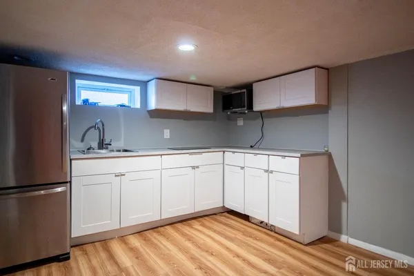 a kitchen with granite countertop white cabinets and refrigerator