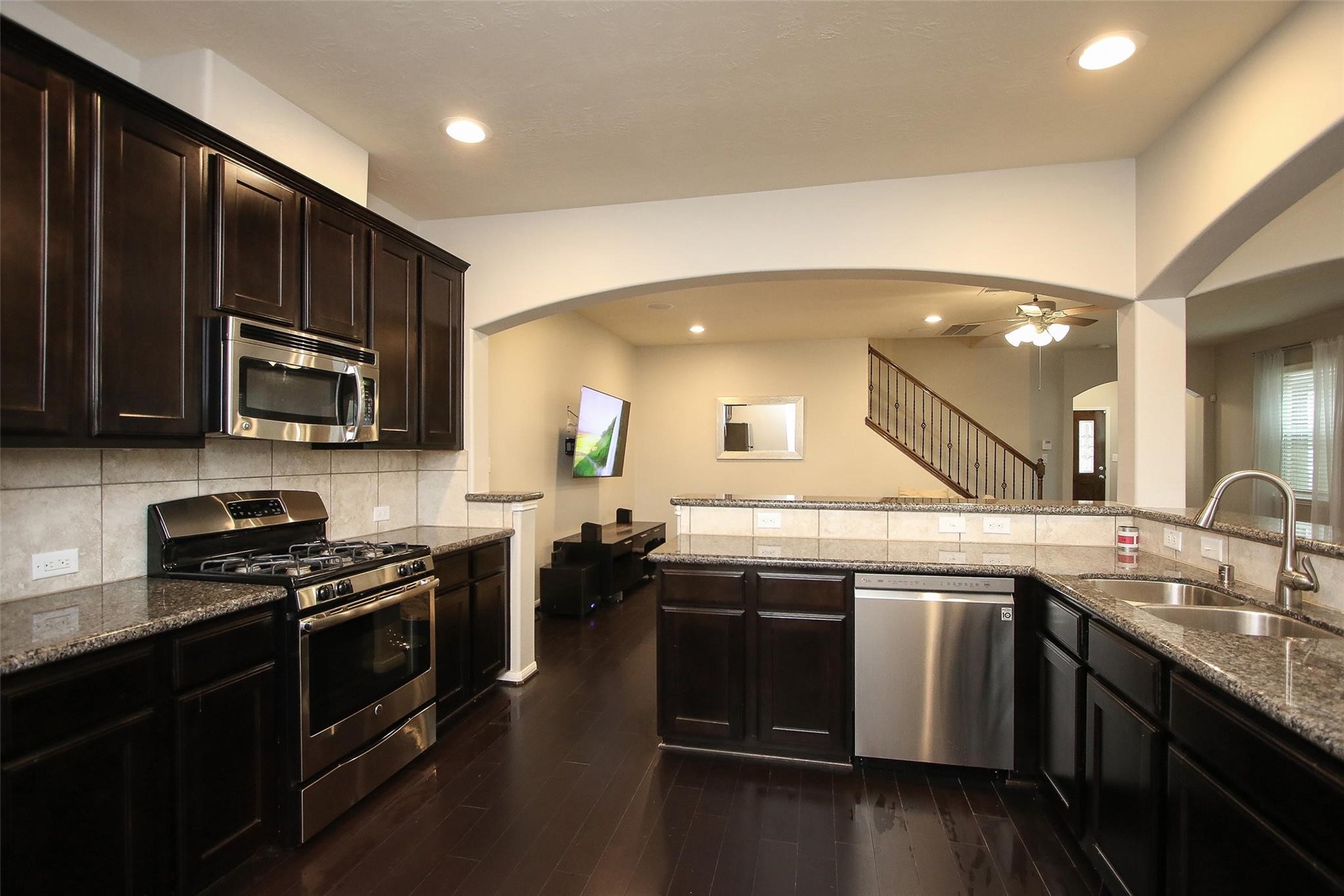 8517 Sunset Loch Drive Spring, TX 77379 - Photo 12 of 22 a kitchen with stainless steel appliances a sink dishwasher a stove top oven a refrigerator with wooden floors and a stove
