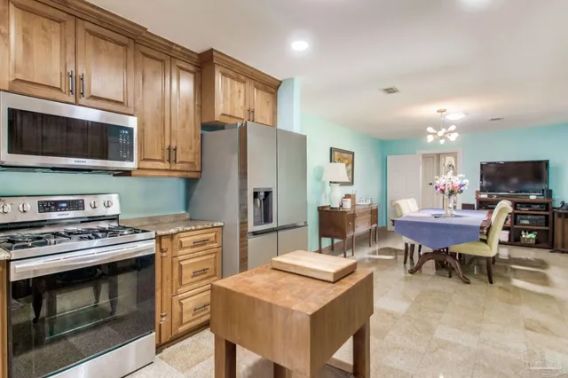 a kitchen with stainless steel appliances a stove a refrigerator a stove a dining table and chairs