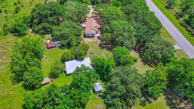 an aerial view of residential house with outdoor space and trees all around