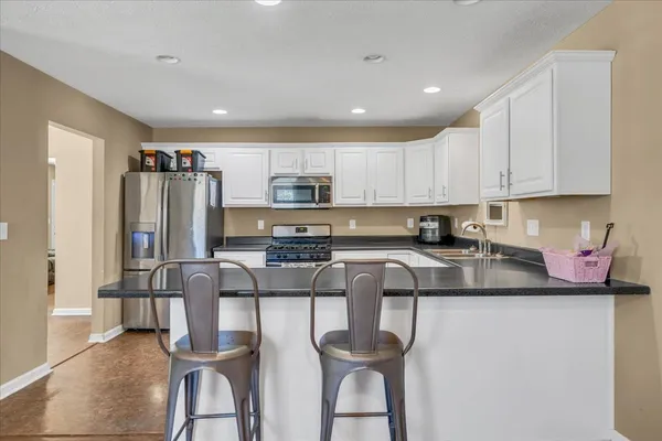 a kitchen with stainless steel appliances granite countertop a sink refrigerator and cabinets