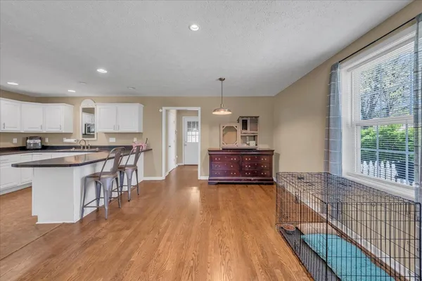 a kitchen with stainless steel appliances granite countertop a stove top oven a sink dishwasher a refrigerator and white cabinets with wooden floor