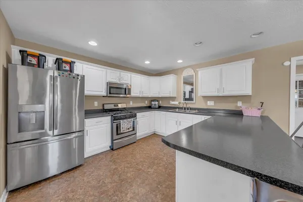 a kitchen with stainless steel appliances granite countertop a refrigerator a stove and a sink