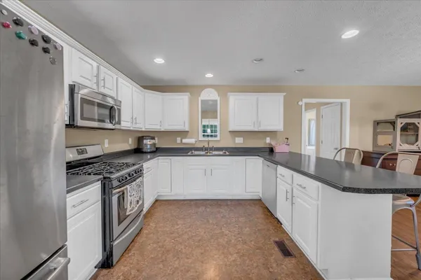 a large kitchen with stainless steel appliances granite countertop a stove a sink and a microwave
