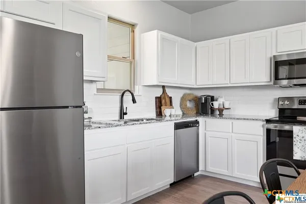 a kitchen with stainless steel appliances granite countertop a refrigerator sink and white cabinets