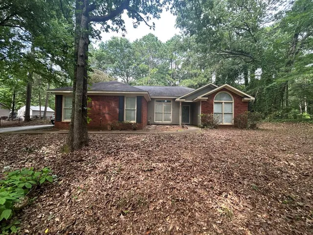 a front view of a house with a garden and trees
